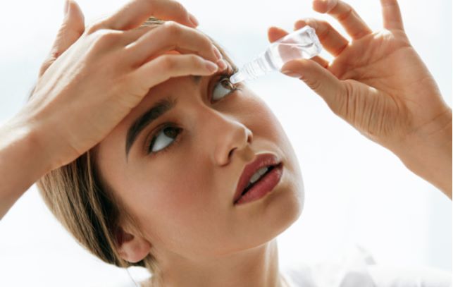 Women looking up to apply eye drops to her dry eyes