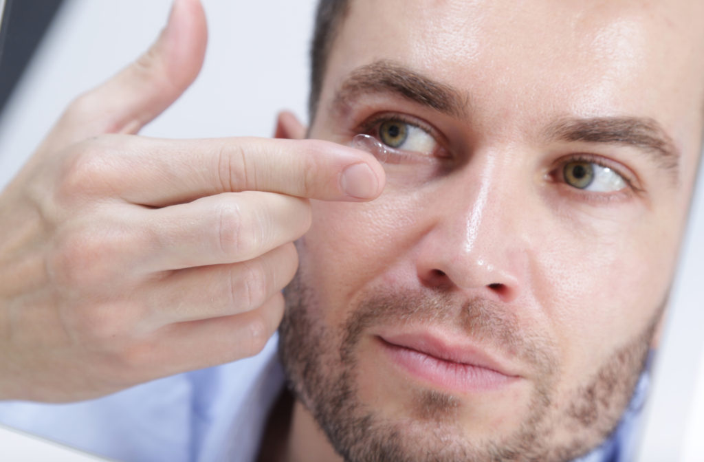 Close up of man putting in contact lens into eye
