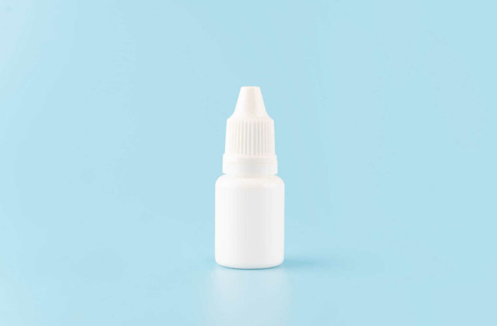 A bottle of eyedrops against a blue background.