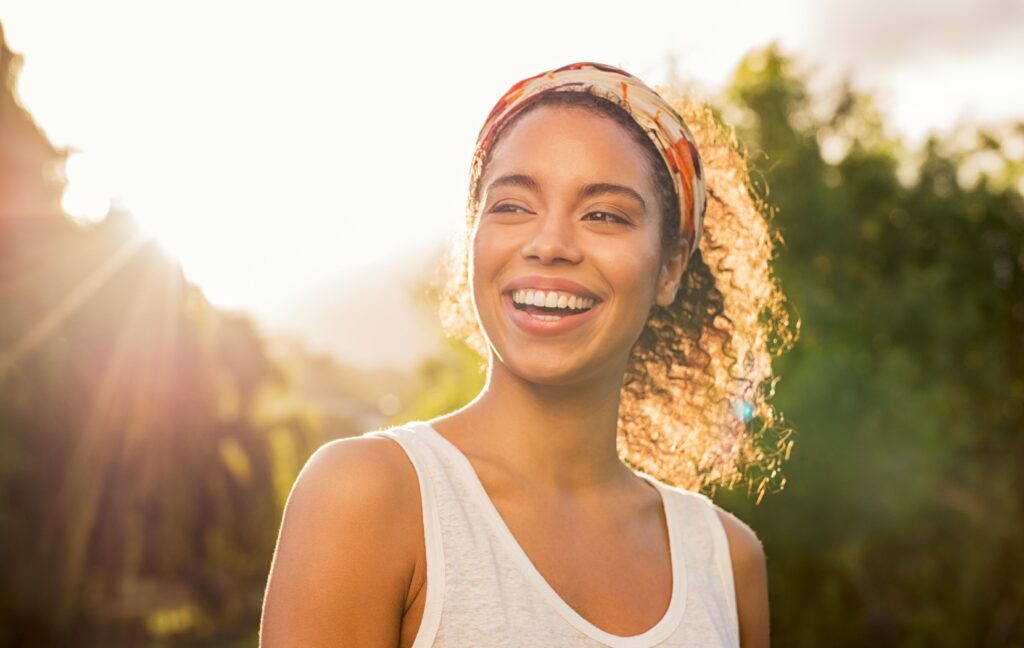 A person with bright, clear eyes smiles in the sunlight after receiving treatment for meibomian gland dysfunction.