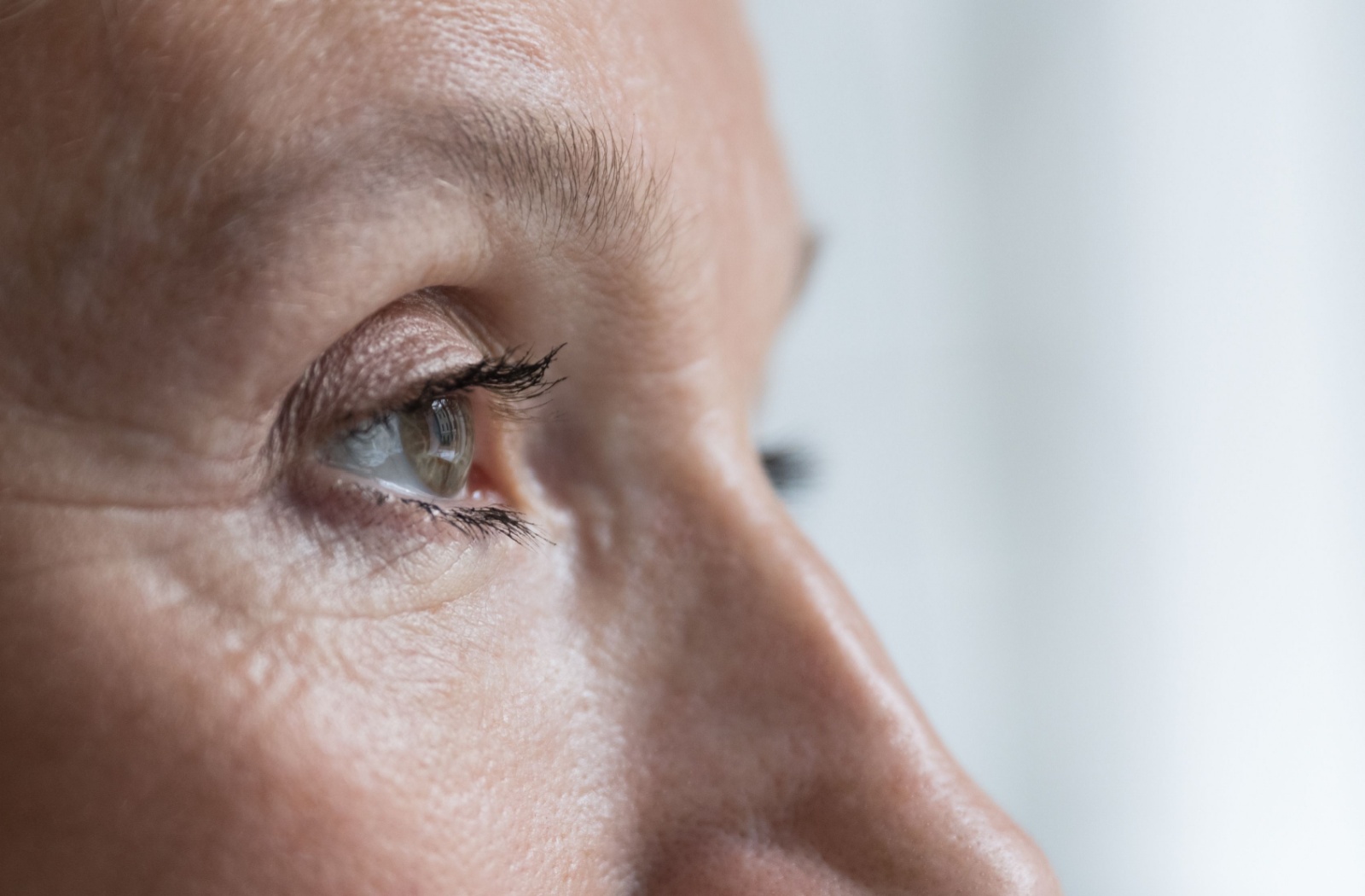 Close-up of a person over 50's eye as they look out a window.