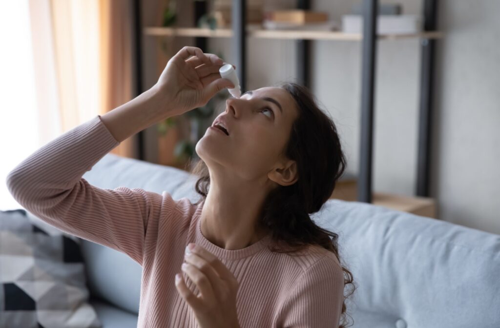 A person leans their head back to apply eyedrops to soothe dry eyes.