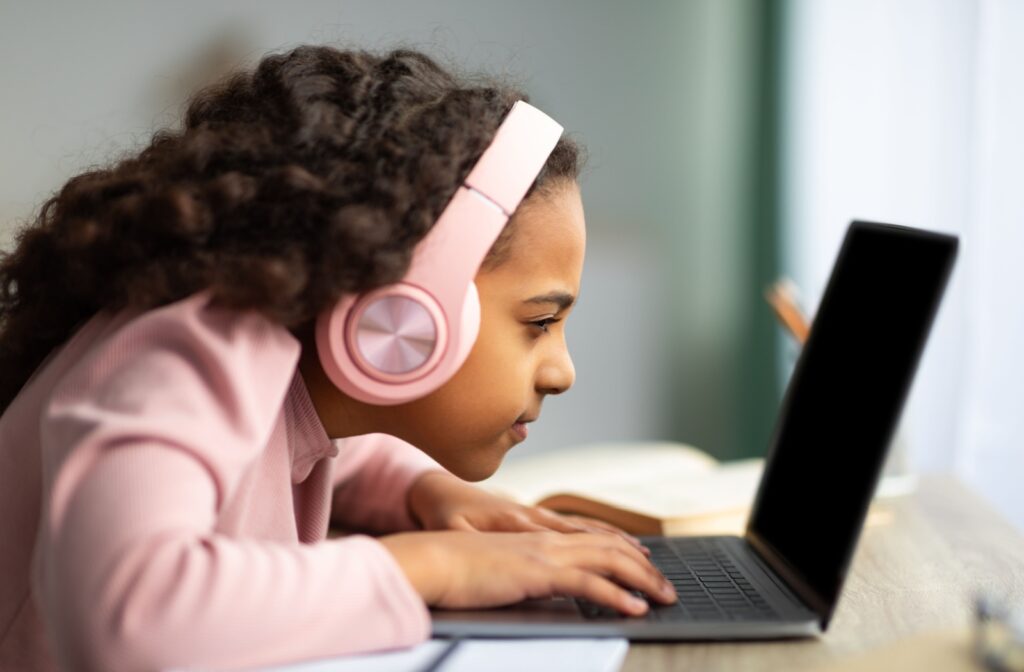 A child with myopia squints and leans too close to their computer screen.